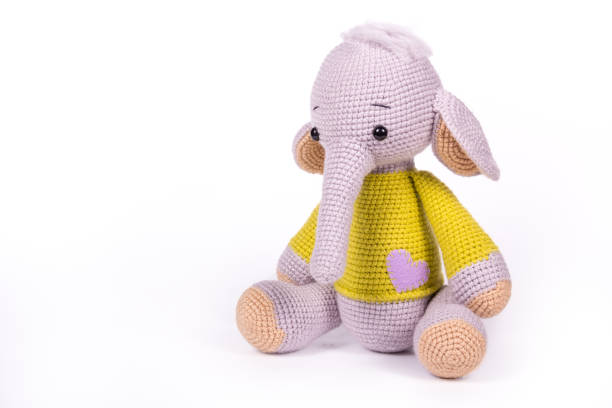 Little knitted baby elephant on white background. Baby elephant toy sitting on white background. Copy space stock photo