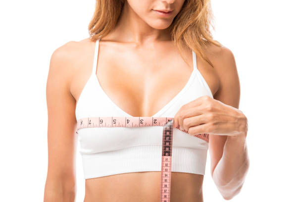 woman measuring her chest size over white background - sensuality horizontal indoors studio shot imagens e fotografias de stock