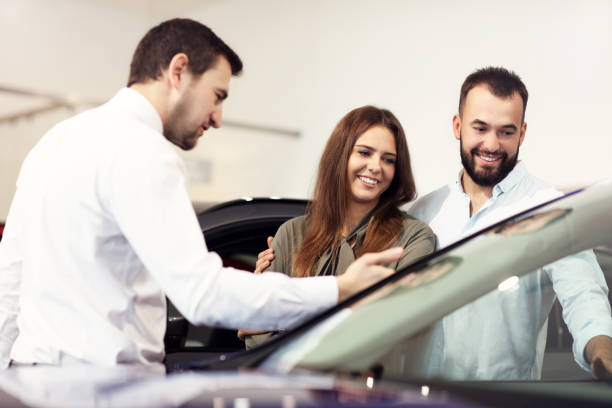istock Confident young salesman explaining car features to the young attractive owners 1063840244