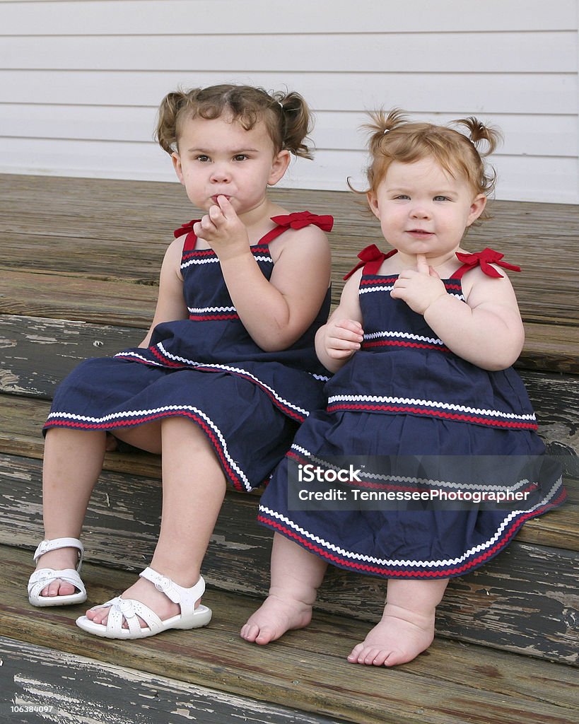 Deux petites filles assis sur un porche de soleil - Photo de Blanc libre de droits