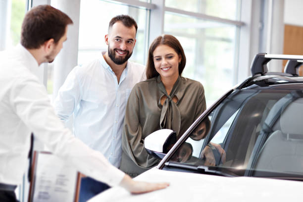 istock Confident young salesman explaining car features to the young attractive owners 1063841480