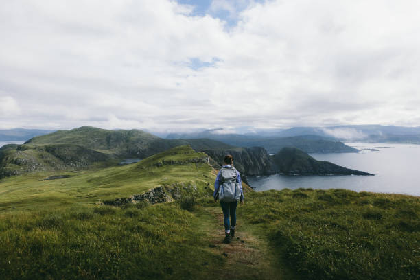 frau mit rucksack wandern auf runde insel in norwegen - mountain peak norway reflection sunlight stock-fotos und bilder