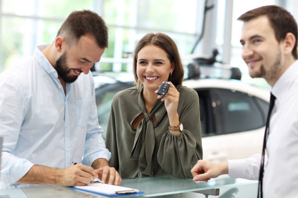 istock Confident young salesman explaining car features to the young attractive owners 1063842962