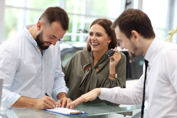 istock Confident young salesman explaining car features to the young attractive owners 1063843006