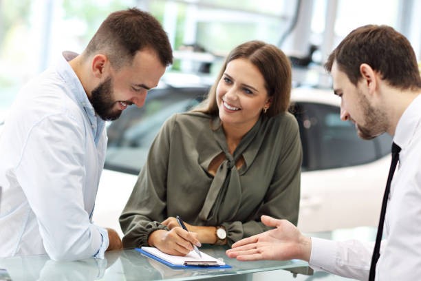 istock Confident young salesman explaining car features to the young attractive owners 1063843054