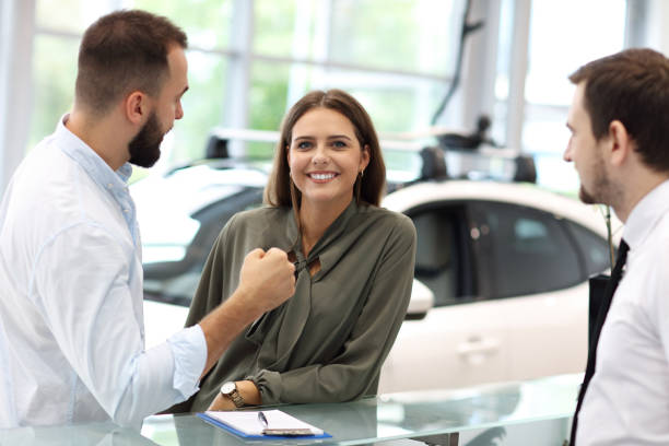 istock Confident young salesman explaining car features to the young attractive owners 1063843080