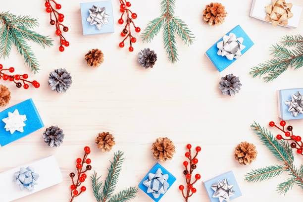 istock Fir branches, cones, red decorative berries and blue and white gift boxes are spread out in a circle. Christmas composition, frame. In the center of Copy Space. Festive photo. 1063843334