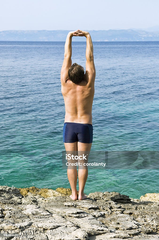 Hombre caucásico de estiramiento en rocas - Foto de stock de Adulto libre de derechos