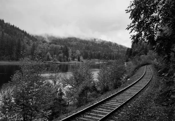 a black and white image of railroad tracks beside a river
