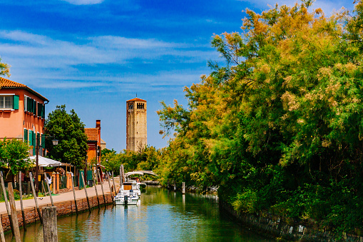View of bell tower of Torcello Cathedral over canal and trees on the island of Torcello, Venice, Italy