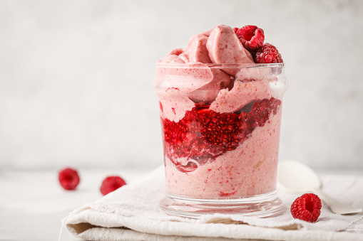 Vegan breakfast raspberry smoothie (ice cream) with berry jam in a jar. Plant based diet concept.