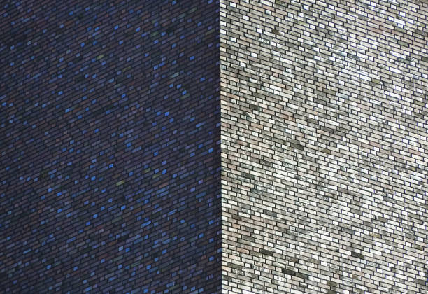 Close up outdoor view of a wall stone bricks corner. Half part of the wall is lighted by the sun, the other part is in the shadow. Pattern with beige brown rectangular elements.