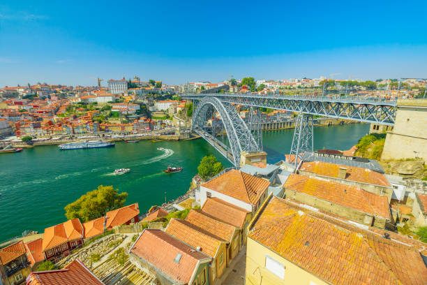 boats cruising under Douro River in Porto. Aerial view of Dom Luis I Bridge, Ribeira Waterfront and Rabelo boats from Vila Nova de Gaia, Porto, Portugal. Oporto urban cityscape.