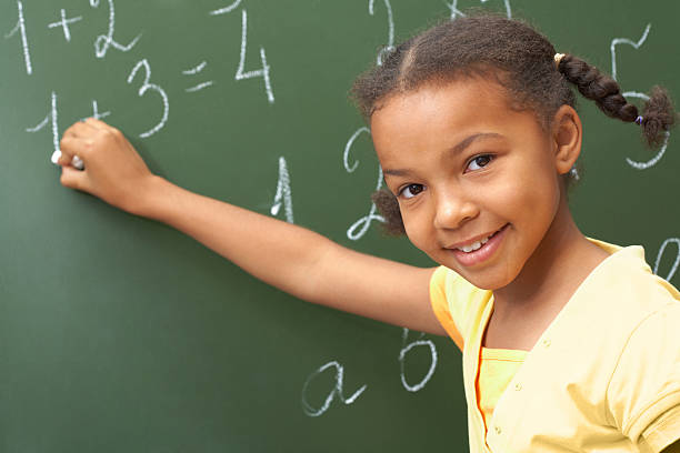 istock A young girl writing on a chalkboard 106387468
