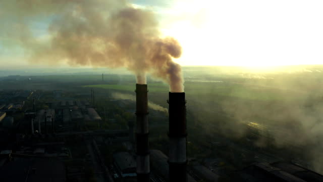 Industrial zone with a large red and white pipe thick white smoke is poured from the factory pipe in contrast to the sun. Pollution of the environment: a pipe with smoke. Aerial view