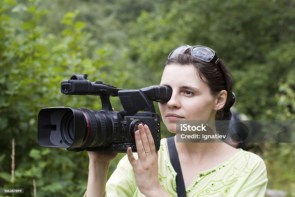 Woman with digital video camera. Camera woman is filming outdoors Adult Stock Photo