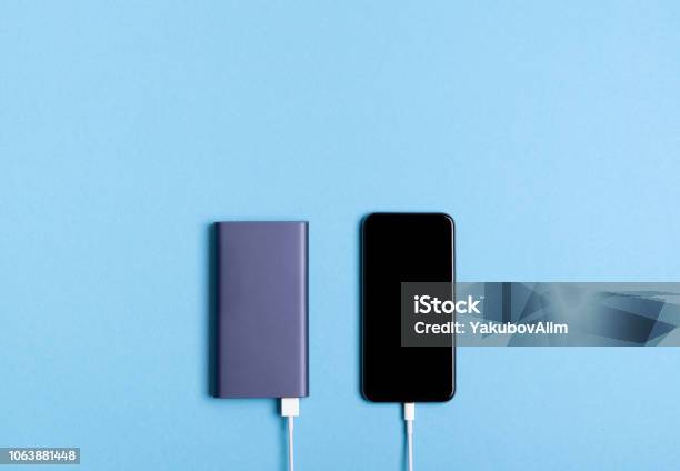 Smartphone Charging With Power Bank On Blue Background Stock Photo - Download Image Now