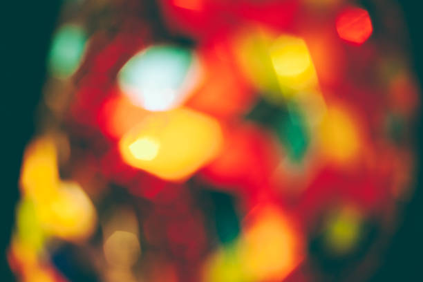 Red lollipop in the form of a New Year tree against the backdrop of garland lights.