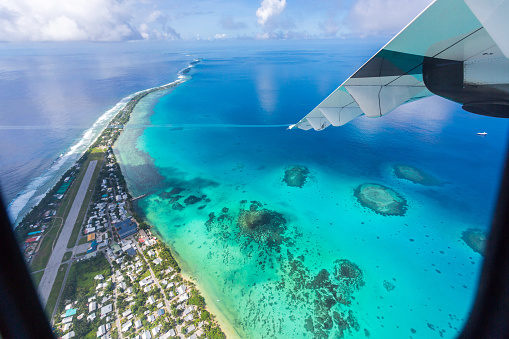 Tuvalu under the wing of an airplane. Aerial view of Funafuti atoll and the airstrip of International airport in Vaiaku. Fongafale motu. Island nation in Polynesia, South Pacific Ocean, Oceania.