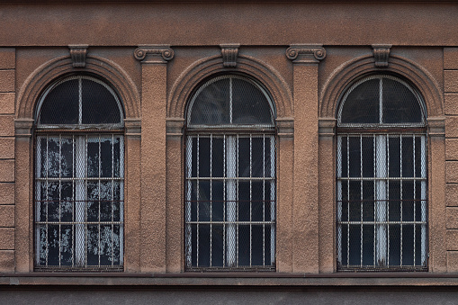 Three arched windows on an old ornate facade