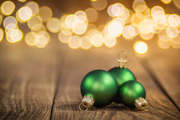 Green Christmas balls on rustical wood, defocused light bokeh background