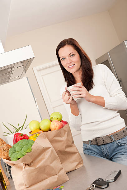 istock Young smiling woman with groceries in the kitchen 106390102