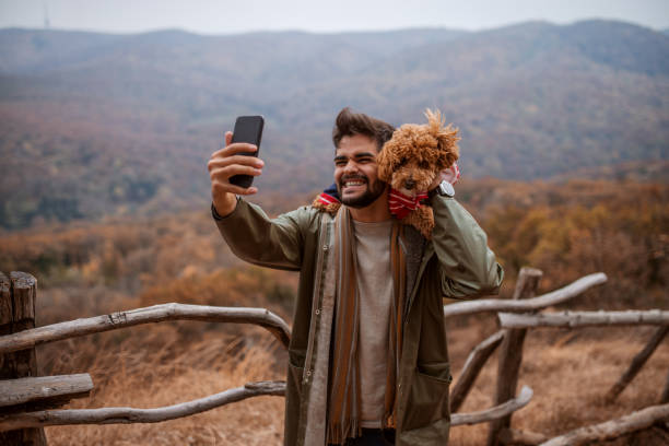 istock Man taking self portrait with dog on shoulders in nature. 1063901838