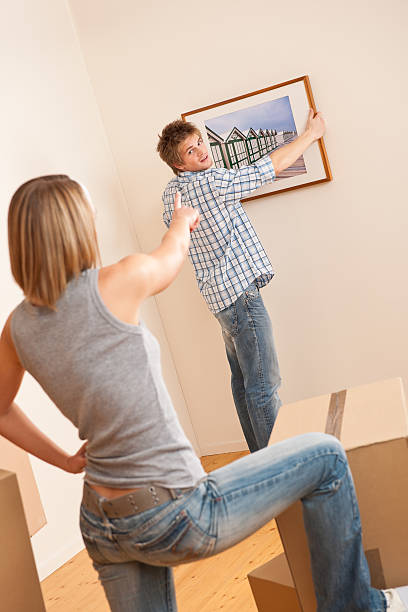 istock Moving house: Couple hanging picture with frame on wall 106390200