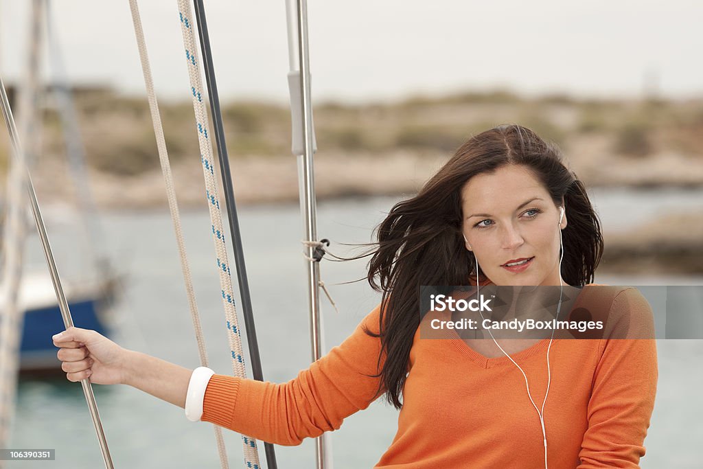 Attraente donna in piedi sulla barca a vela con cuffie - Foto stock royalty-free di Acqua