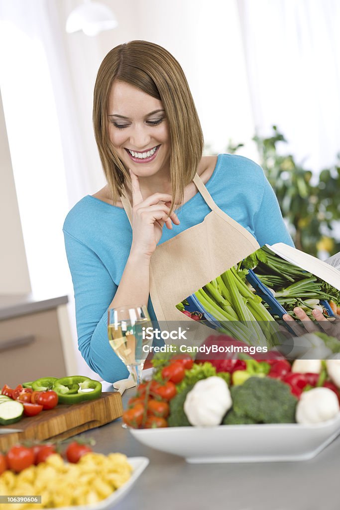 COCINA-mujer sonriente sostiene recetas, con pasta y verduras - Foto de stock de 20 a 29 años libre de derechos