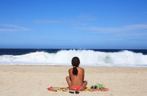woman sitting and sunbating in copacabana beach in rio de janeiro in brazil