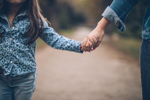 Mother and daughter holding hands in public park
