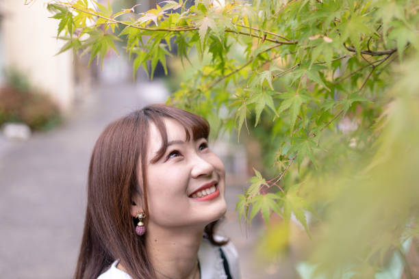 istock Young woman looking up maple leaves 1063918554