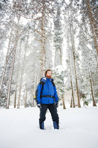 istock Bearded young mountain climber standing in deep powder snow, surrounded by tall fir trees 1063936376