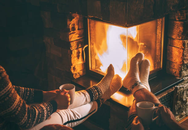 paar verliefd zitten in de buurt van open haard. benen in warme sokken close-up in beeld. cozy christmas huis sfeer - fireplace stockfoto's en -beelden