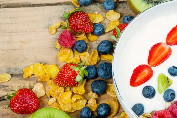 Healthy breakfast concept. Fresh berries with a bowl of yogurt and cornflakes on the wooden table