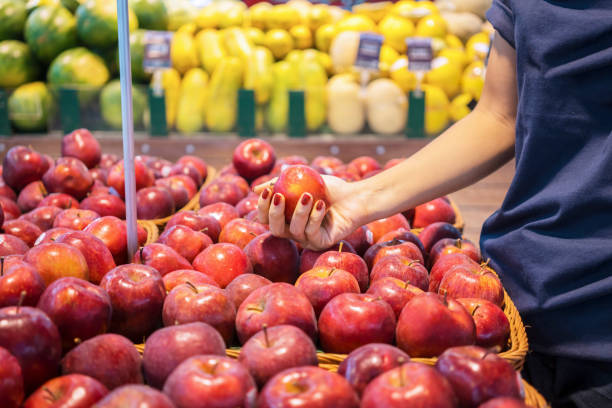 istock Woman hand pick up red apple fruit in market 1063945232