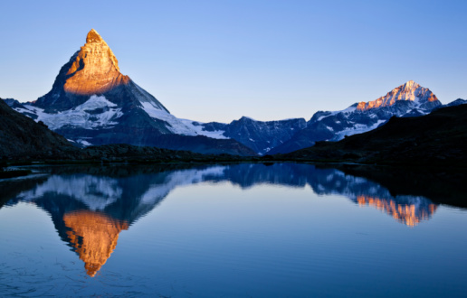 First lights at dawn over the top of Matterhorn (4478m) and Dente Blanche (4357m) reflected in the Riffelsee (Switzerland)