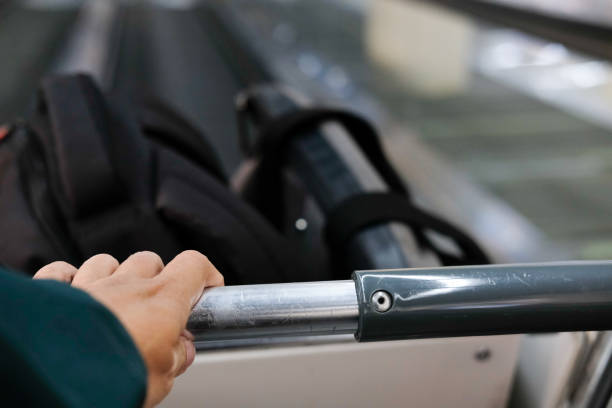 istock hand hold luggage baggage cart trolley on escalator 1063947574