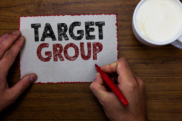 istock Word writing text Target Group. Business concept for Particular people that an advertisement intended to reach to Man holding marker communicating ideas piece paper wooden table cup coffee. 1063948526