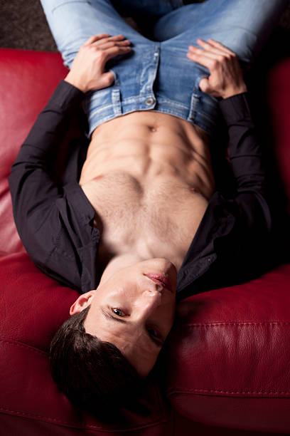 istock Sexy young man is lying on the red sofa 106396400