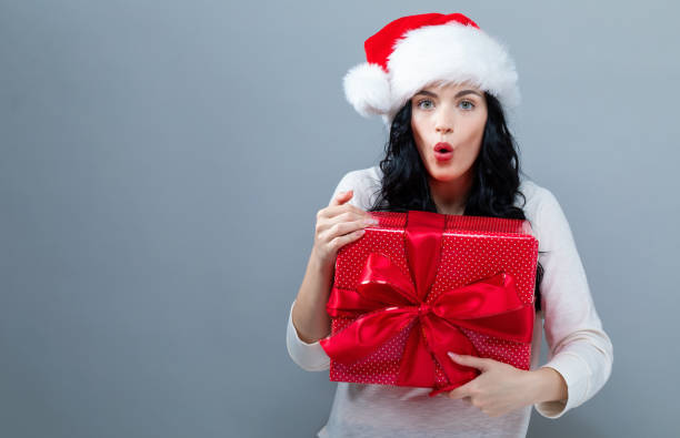 istock Young woman with santa hat holding a gift box 1063967890
