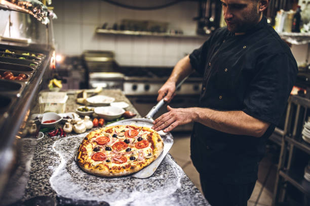 szef kuchni wyjmuje gorącą pizzę z pieca - pizzeria zdjęcia i obrazy z banku zdjęć