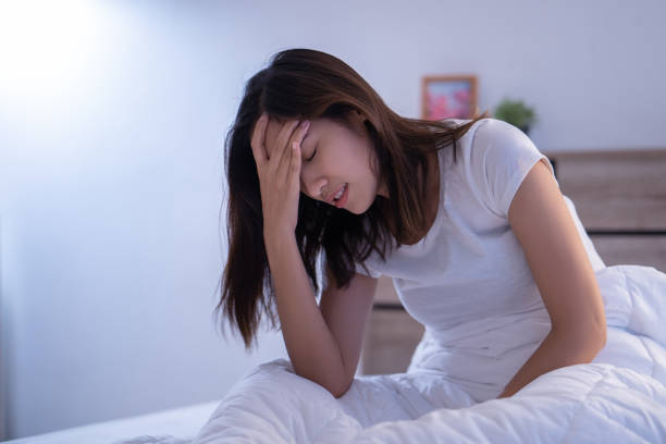 азиатская женщина головная боль может быть мигрени утром на кровати - evil стоковые фото и изображения
