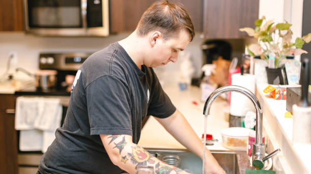 istock Young man washing dishes in apartment kitchen 1063976554