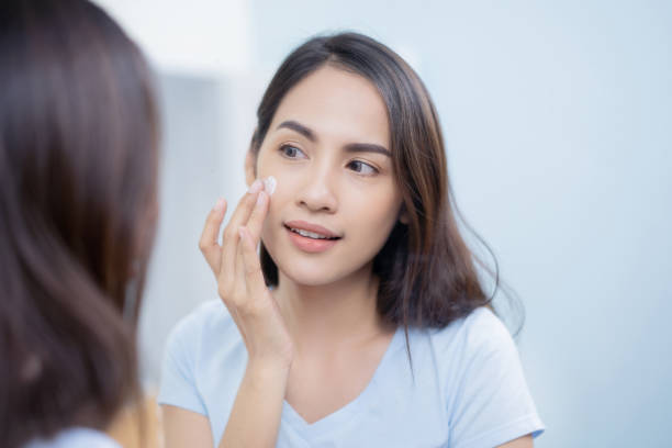 asian women applying face lotion. - applied science imagens e fotografias de stock