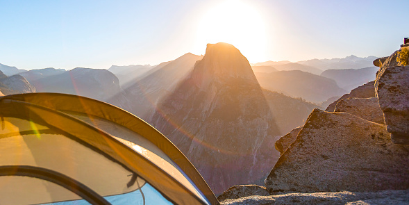 Tent in Glacier Point with Half Dome at sunrise. Tent on a camping site in Glacier Point, Yosemite, California. The site has an amazing view of the bright sunrise behind the unique Half Dome.