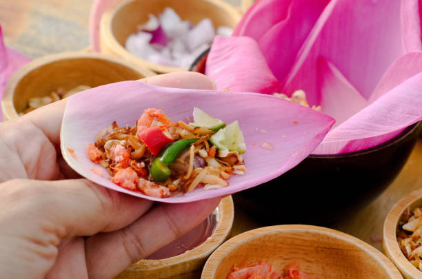 One bite wrap with red lotus petal (Maing Kam) that isThai and Laos traditional snack is on the wood table