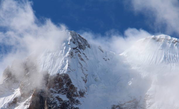 istock Snowy mountain peaks under blue sky and white clouds 1064016876