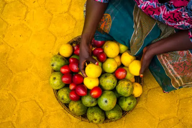 Close up on woman hands and colorful tropical fruit in a basket. Rwanda, Africa